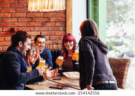 Waitress Bringing Beer Nuts To Group Of Friends In Tavern