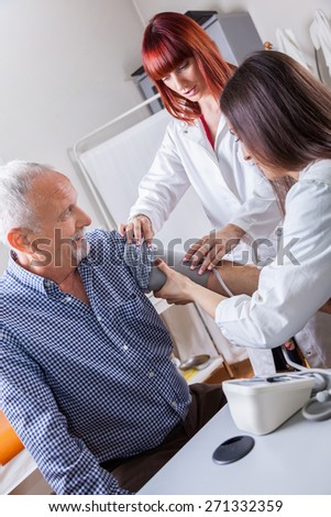 Doctor Checking Blood Pressure To A Mature Man At Doctor's Office.