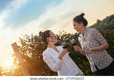 Two Beautiful Young Women Drinking Wine In Vineyard