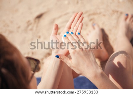 Woman Spreading Sun Lotion On The Beach