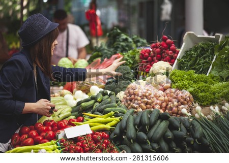 Young Female Choosing Vegetables At Market Place