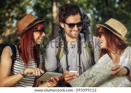 Three Tourists In Nature Browsing Map Using Digital Tablet