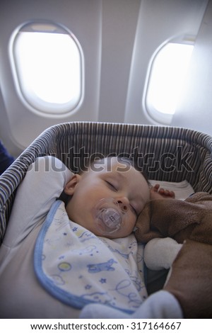 Adorable Baby Boy Sleeping In Special Bassinet On Airplane