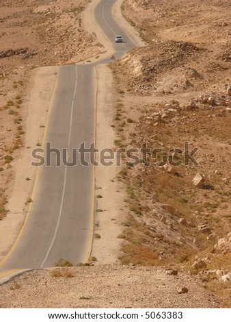 Desert highway with a car approaching, arid soil, stone desert, King\'s Highway, Jordan, Middle East