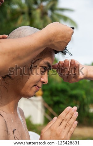 BANGKOK, THAILAND - JULY 28 : Thai man gets his head shaved by a monk during a Buddhist ordination ceremony on July 28, 2012 in Bangkok, Thailand.