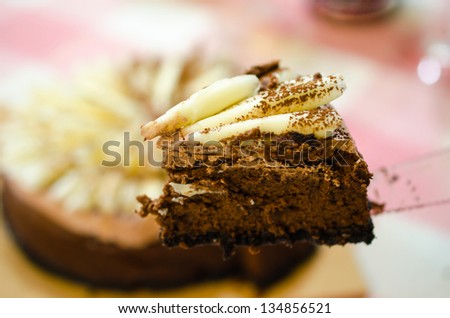 Cut piece of cake on knife on the background of the whole cake.