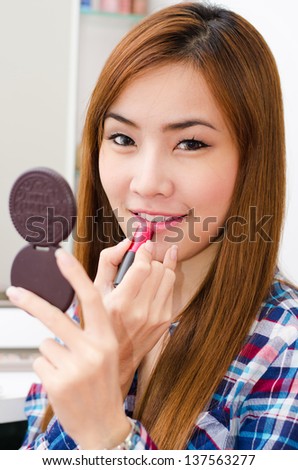 Attractive Asian cute girl applying lipstick