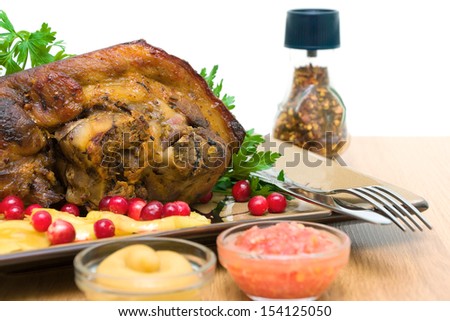 roasted pork knuckle with baked apples and cranberries close-up. horizontal photo.
