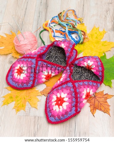 a pair of knitted slippers close-up and autumn leaves. top view - horizontal photo.