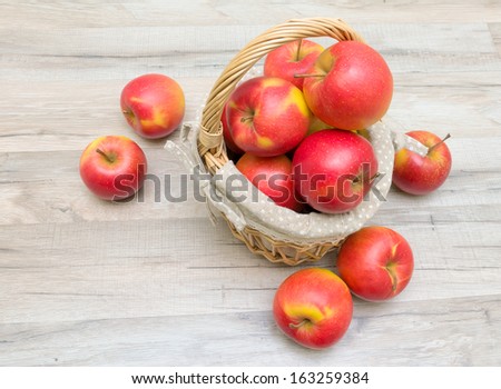 basket with ripe red apples on wooden table close up. horizontal photo.