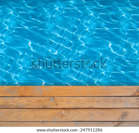 Swimming pool with blue clear water and wooden deck