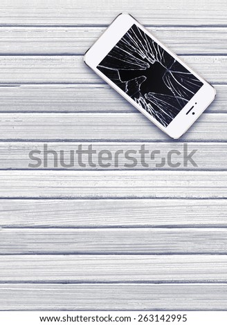 Modern mobile phone with broken screen on white wooden background