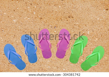 colorful beach shoes on yellow sand background