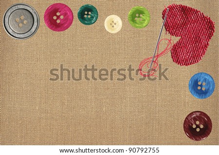 Bright sewing buttons, red textile heart and needle on gray fabric