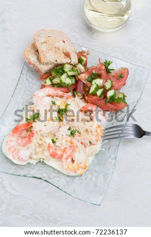 An angled top view garlic shrimp linguine with a mandarin-garlic cream sauce, side of a tomatoes,cucumbers and parlsey salad and garlic toast, glass of white wine on an off-white cotton tablecloth