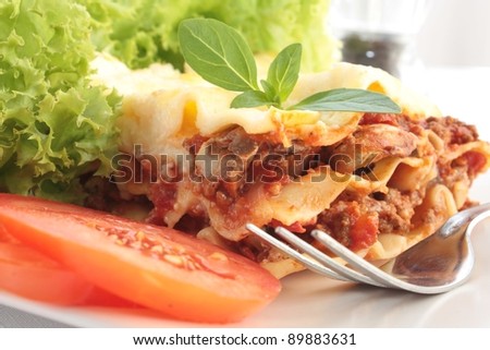 Close-up of a piece of lasagna served with a simple side salad.