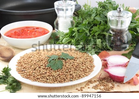 Ingredients for lentil soup including dried lentils, chopped tomatoes, onions, fresh parsley and salt and pepper.