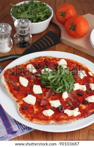 Pizza with ham, ricotta cheese and rocket salad.