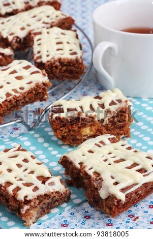 Brownies or cake bars covered in white chocolate with a cup of tea