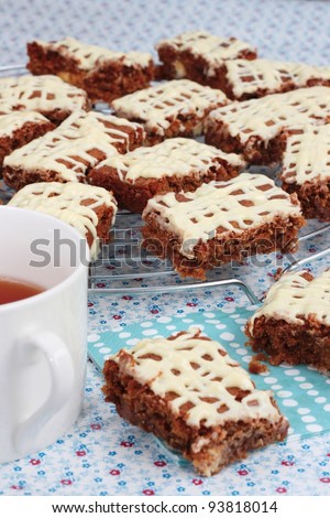 Brownies or cake bars covered in white chocolate with a cup of tea