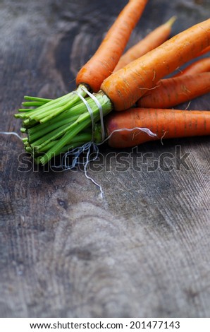 bunch of fresh raw carrots. old wooden surface. black background.