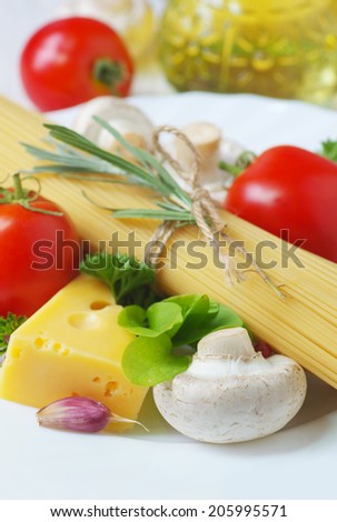 Pasta spaghetti, cheese, vegetables and spices on a white plate. Italian food ingredients and olive oil.