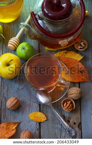 Freshly brewed tea, apples, honey and autumn leaves. Food on the old wooden table.