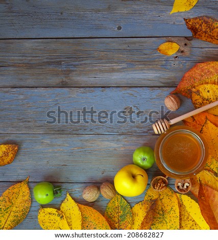 Autumn background with leaves, apples, nuts and honey. Frame of yellow leaves. Old wooden board.