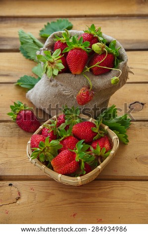 Ripe strawberries in a sack. Harvest berries. Old wooden table.
