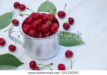 Ripe cherries in a metal mug. Harvest berries. space for text. white wooden table