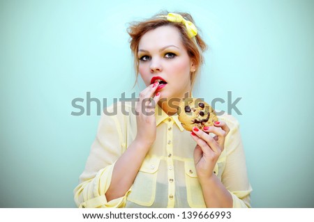 Young attractive woman eating a smiling chocolate chip cookie.