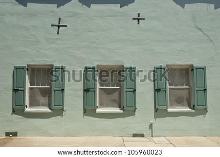 The stucco wall and windows of a house from the 1800\'s, in Charleston South Carolina, with repaired earthquake damage.