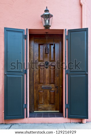 The front door and decorative brass fixtures of a pink Victorian Era house.