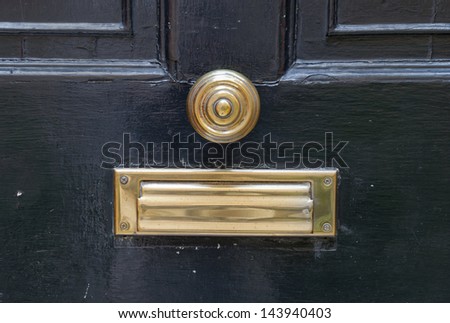 An old seventeenth century brass doorknob centered in the middle of the door with mail slot.