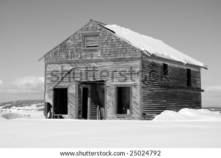 An old commercial shop or mercantile sits in a snow covered field.