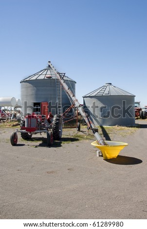 A pair of grain bins and a tractor driven auger.