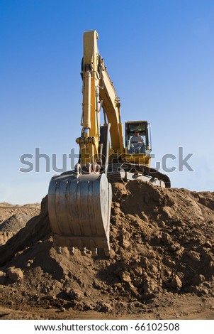 A large track hoe sits on top of a pile of earth or dirt.