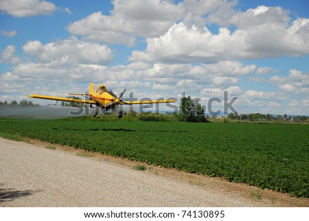 A spray plane or crop duster applies chemicals to a field of crops.