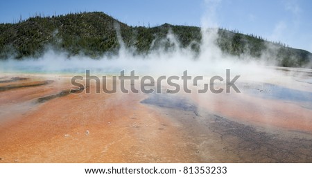 A panorama of rust colored minerals, blue water and steam at the Grand Prismatic Geyser at Midway Geyser Basin in Yellowstone National Park.