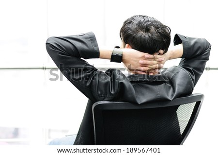 Back view of Businessman relaxing in black chair