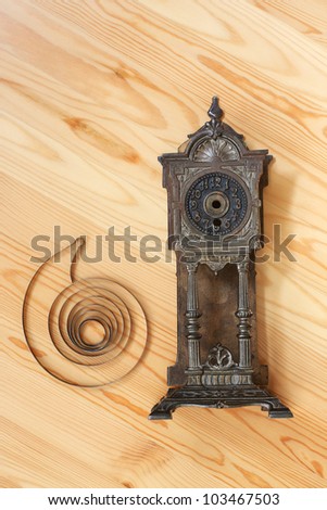 Body and mainspring of old clock on light wood