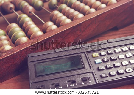 Old wooden abacus and obsolete mathematic  calculator. Retro toned image.