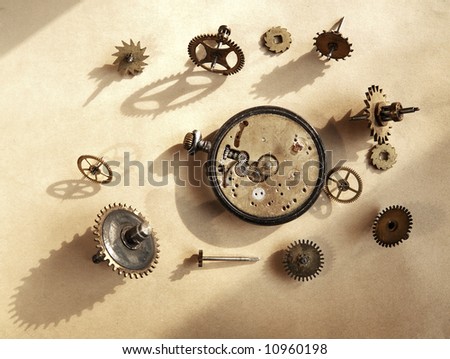 Broken watch and watch cogwheels over old paper