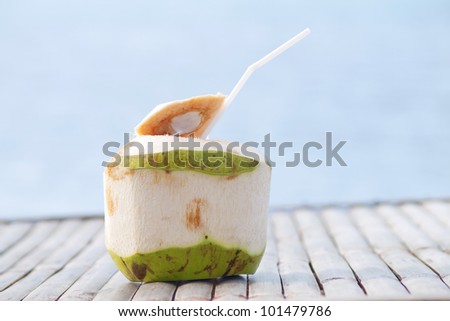Coconut Water Drink on bamboo table with sea background