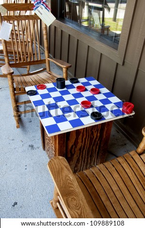 Rocking chairs sit before a wooden checker board with game pieces.
