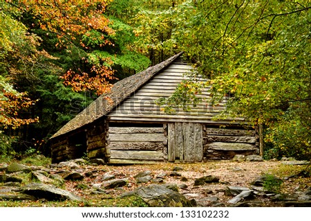A rustic cabin sits surrounded with fall colors.