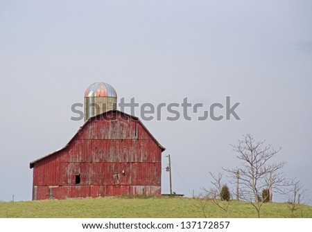 A lone red barn stands in an open field.