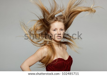 Fine art fashion portrait of blond fashion model posing with hair fluttering in the wind