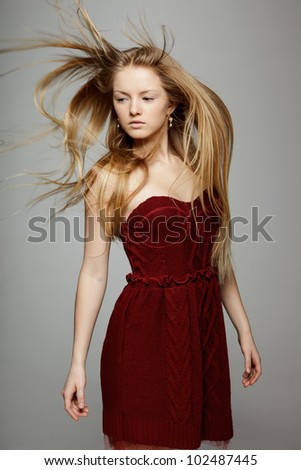 Fine art fashion portrait of blond fashion model posing with hair fluttering in the wind