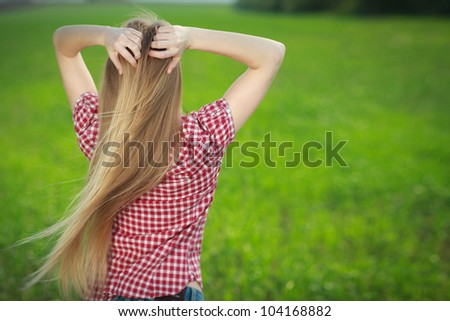 The back of an attractive young woman relaxing with hands behind her head